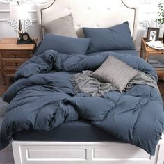 an unmade bed with blue comforter and pillows on it in a white bedroom