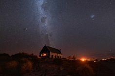 a small house sitting on top of a hill under a night sky