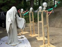 a row of wooden poles with heads on them in front of a parking lot filled with cars