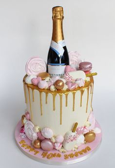 a birthday cake with a bottle of champagne on top and candies all around it