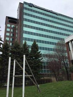 an office building with green grass and trees in the foreground