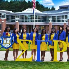 a group of young women standing next to each other in front of a school building