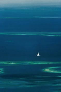 a sailboat floating in the middle of an ocean filled with blue and green water