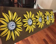 a wooden sign with yellow flowers on it in the middle of a wood flooring area