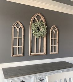 three wooden windows are mounted on the wall above a white dresser with drawers underneath them