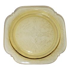 a yellow glass plate with an ornate design on the bottom and sides, set against a white background