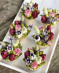 cupcakes decorated with flowers and greenery on a tray