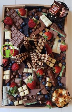 a box filled with lots of different types of chocolates and strawberries on top of it