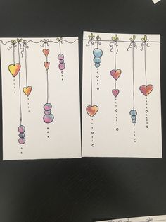 two cards with hearts hanging from strings