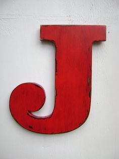 the letter j is painted red and sits on a white wall