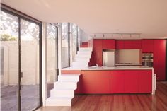 a kitchen with red cabinets and white stairs