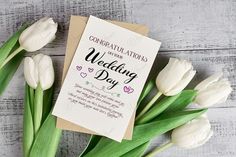 some white tulips are next to a card with the wedding day written on it