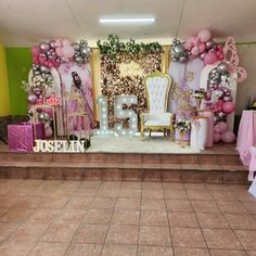 a stage set up for a birthday party with balloons and decorations on the wall,