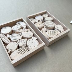 two wooden boxes filled with different types of carved fruit and vegetable designs on top of a table