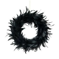 a black feather wreath hanging on a white wall