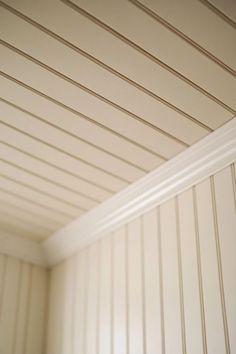 an empty room with white walls and wood paneling on the ceiling is seen in this image