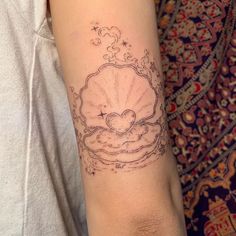 a woman's arm with a tattoo on it that has an image of a shell