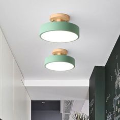 two circular lights hang from the ceiling above a kitchen counter and dining room table in front of a chalkboard wall