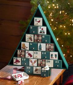 a christmas tree made out of calendars on top of a wooden table next to a christmas tree