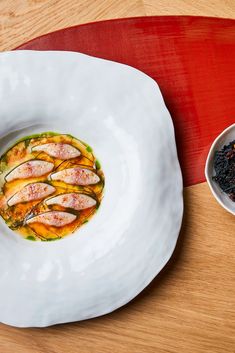 a white plate topped with food next to a bowl filled with black rice and vegetables