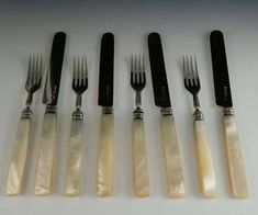 six forks and five knives with mother of pearl in the middle one has black handles