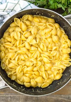 a skillet filled with pasta on top of a wooden table