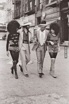 three people walking down the street with one person wearing a hat and another man in a suit