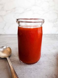 a spoon sitting next to a jar of tomato sauce