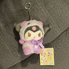 a stuffed animal keychain with a tag hanging from it's side on a blanket