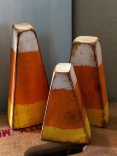 three orange and white striped vases sitting on top of a wooden table next to a pair of scissors