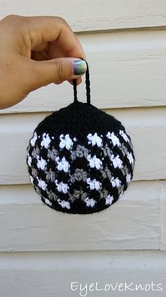 a hand holding a black and white crocheted ornament