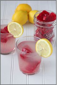 two glasses filled with pink lemonade and raspberry punch on a white table