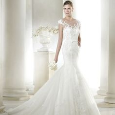 a woman in a white wedding dress is standing near columns and flowers on the floor