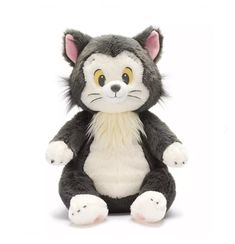 a gray and white cat stuffed animal sitting on top of a white surface with yellow eyes