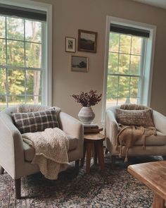 two chairs and a table in a living room with windows on both sides, one chair has a blanket draped over it