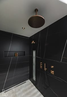 a black and gold tiled bathroom with shower head, faucet, and hand shower