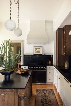 a kitchen with black counter tops and white cabinets, along with a potted plant on the island