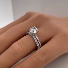 a woman's hand with a diamond ring on top of her finger and the other hand holding an engagement ring