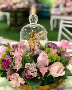 an arrangement of flowers and greenery under a glass clochet on a table