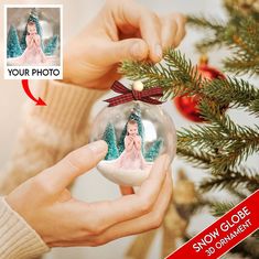 a person holding a christmas ornament with a photo on it and a red ribbon