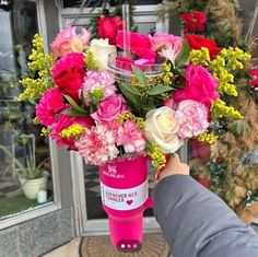 a person holding a pink and white bouquet in front of a store