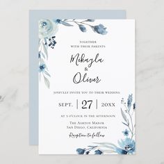 a wedding card with blue flowers and greenery on the front, in watercolor