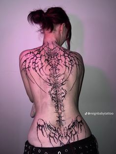 the back of a woman's body with tattoos and piercings on her ribs