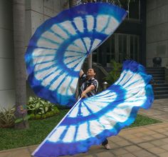 a man holding a blue and white tie - dyed parasol in front of a building