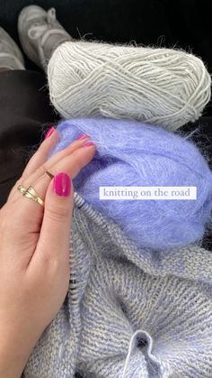 a woman's hand with pink nail polish on her nails next to some yarn