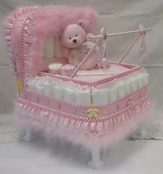 a pink teddy bear sitting on top of a baby crib made out of diapers