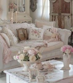 a living room filled with white furniture and lots of flowers on top of the table