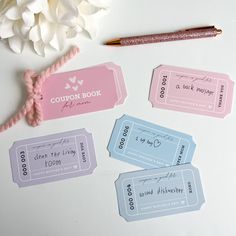 four pink and blue coupons sitting on top of a table next to a pen