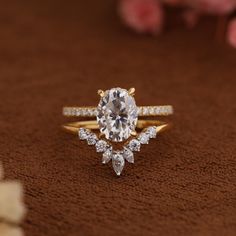 a close up of a diamond ring on a brown surface with flowers in the background