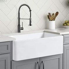 a white kitchen sink sitting under a faucet next to a counter top with utensils